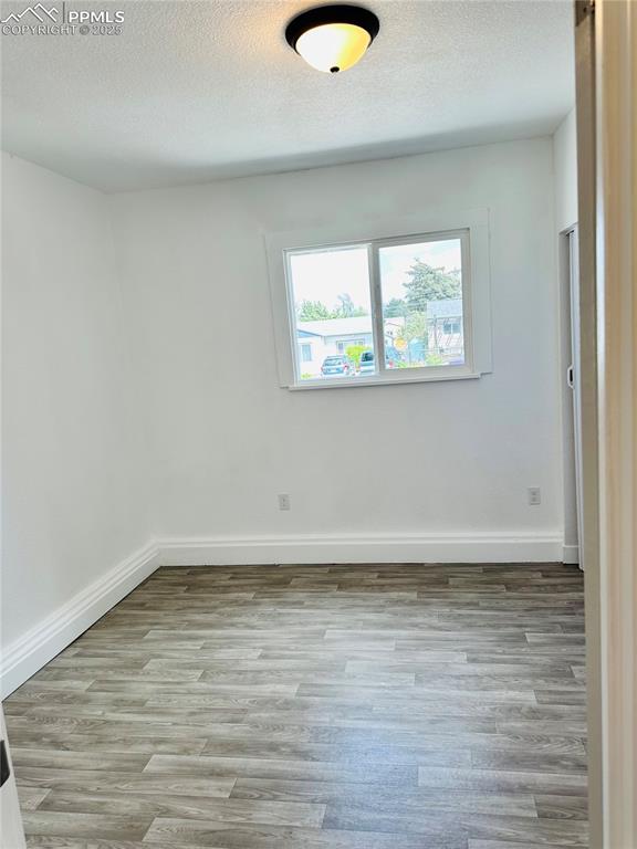 Image 8 of 9: Empty room featuring wood finished floors and a textured ceiling