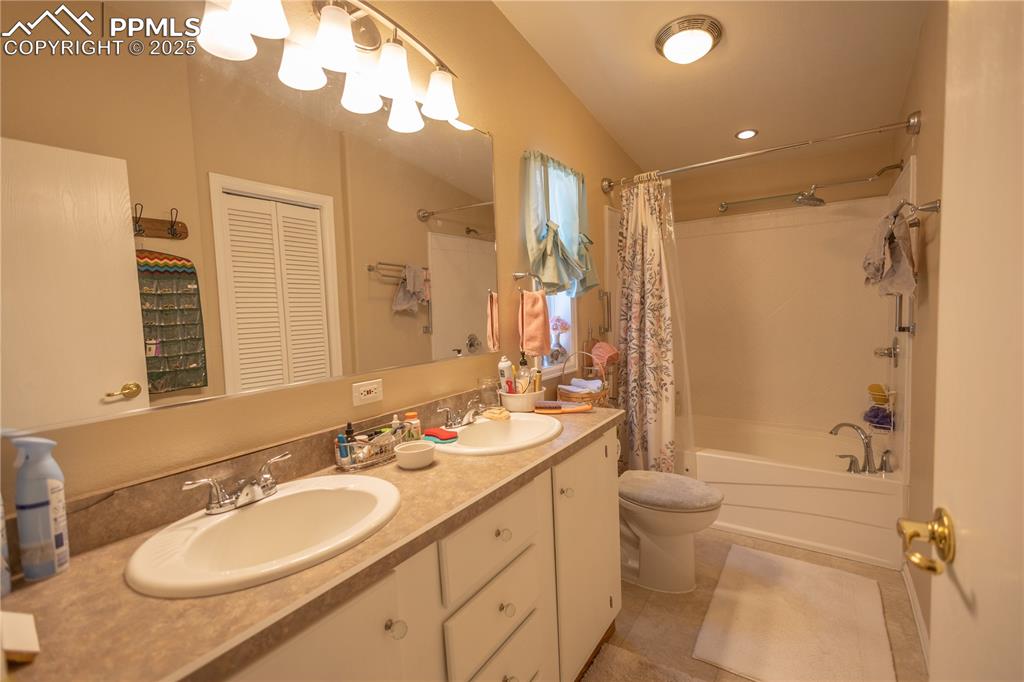 Image 12 of 19: Bathroom featuring shower / bath combination with curtain, double vanity, t