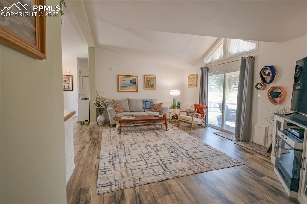 Image 14 of 19: Living area with wood finished floors and high vaulted ceiling