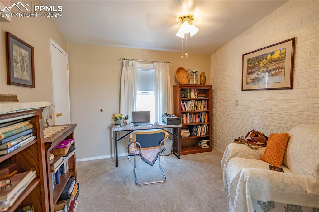 Image 19 of 19: Office featuring ceiling fan, carpet flooring, brick wall, and an accent wa