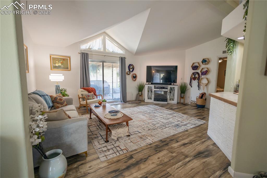 Image 9 of 19: Living area with wood finished floors and vaulted ceiling