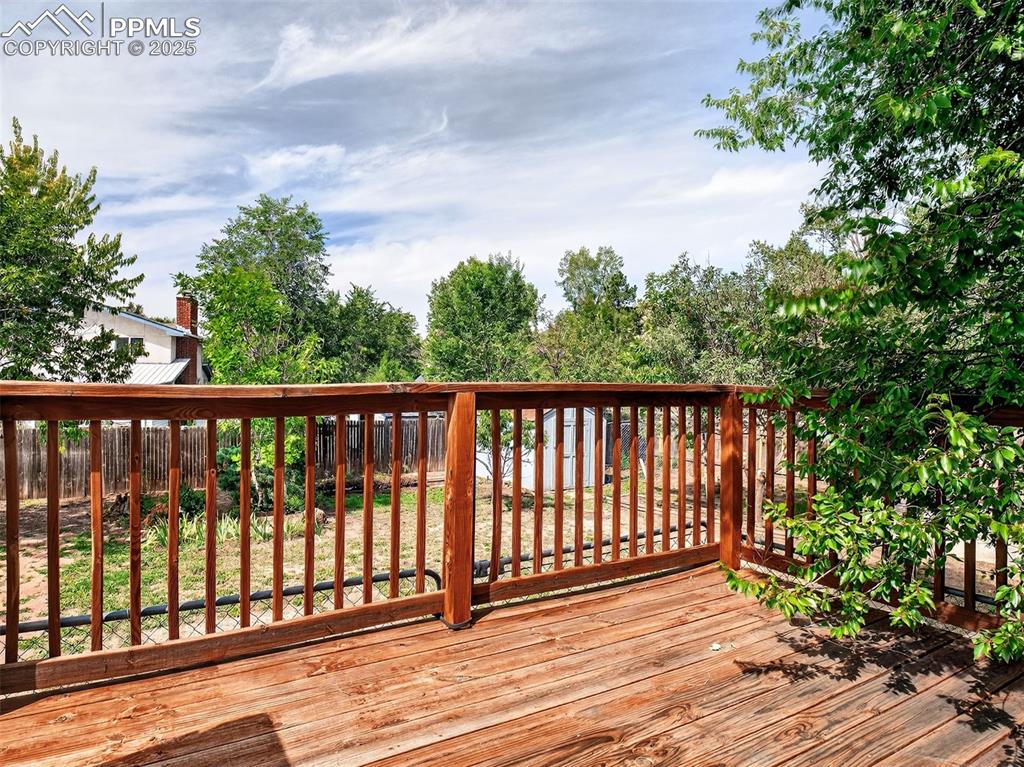 Image 37 of 44: Large wood deck overlooks the fenced in backyard