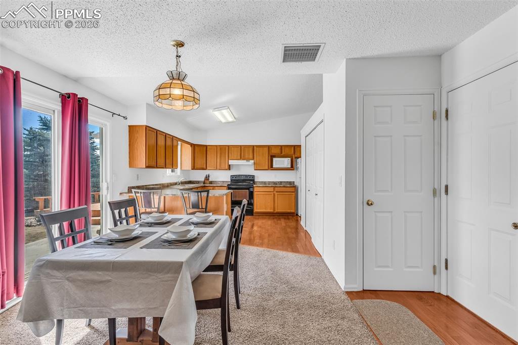 Image 10 of 27: Alternative view of the dining area and kitchen showing the transition to t