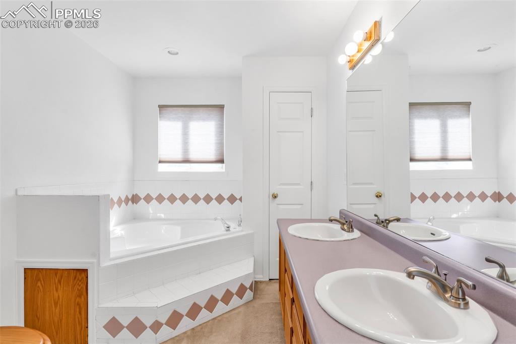 Image 14 of 27: En-suite primary bathroom complete with a dual-sink vanity and a relaxing j
