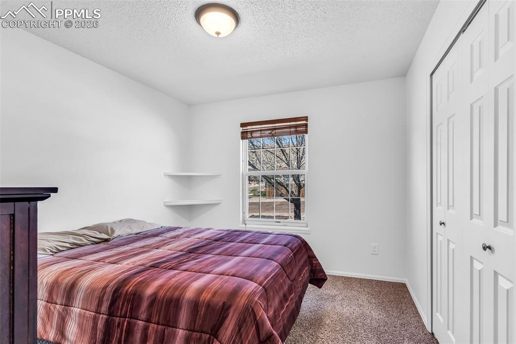 Image 17 of 27: Bright second bedroom with built-in corner shelving, and a large reach-in c