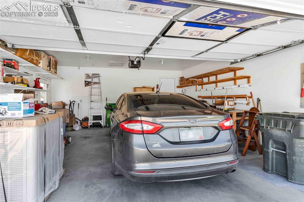 Image 20 of 27: Attached two-car garage featuring insulated doors and extensive built-in sh