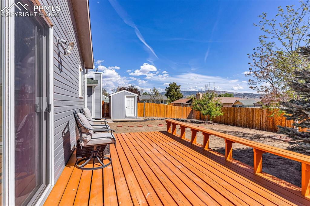 Image 22 of 27: Large wood deck with built-in bench seating, perfect for outdoor dining and