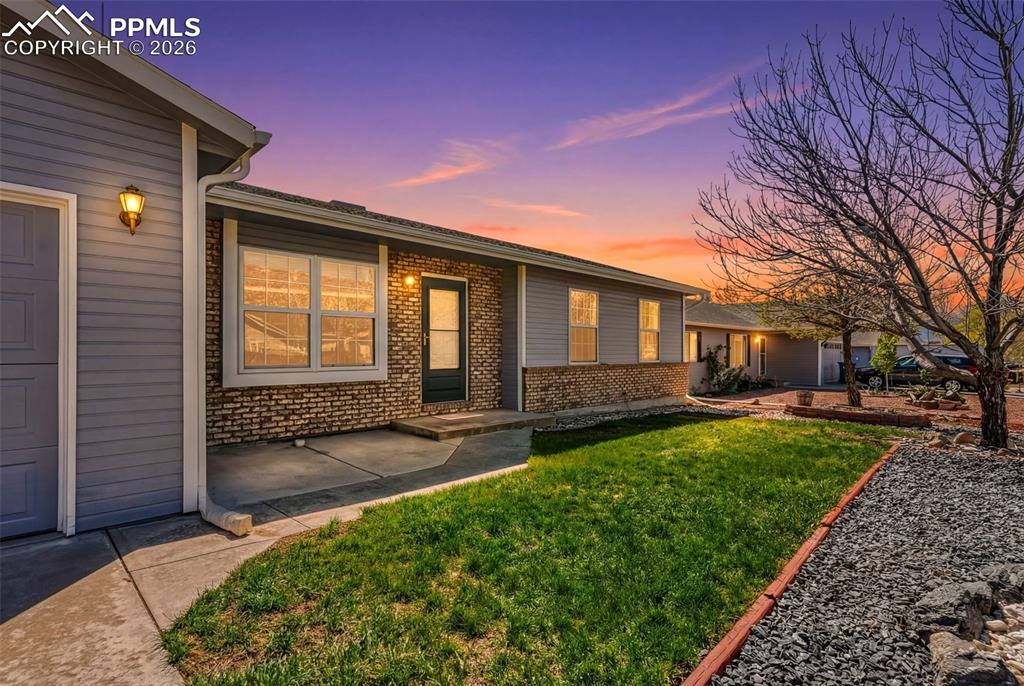 Image 26 of 27: Inviting front entrance highlighted by warm exterior lighting and durable b