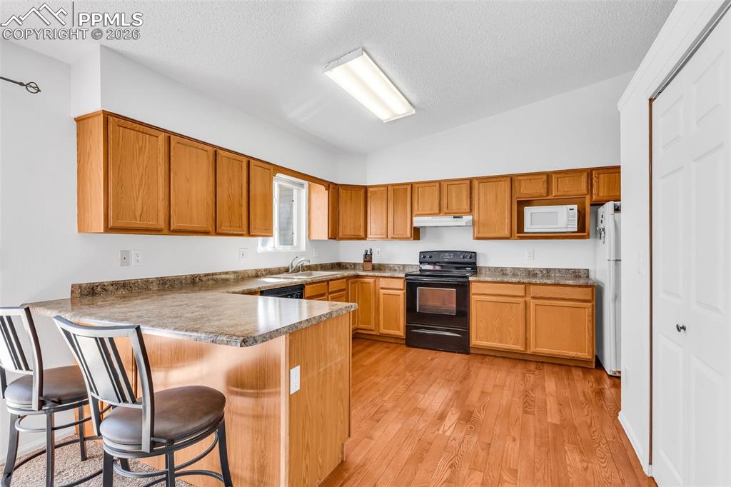 Image 3 of 27: Spacious kitchen featuring ample cabinetry, breakfast bar, and hardwood flo