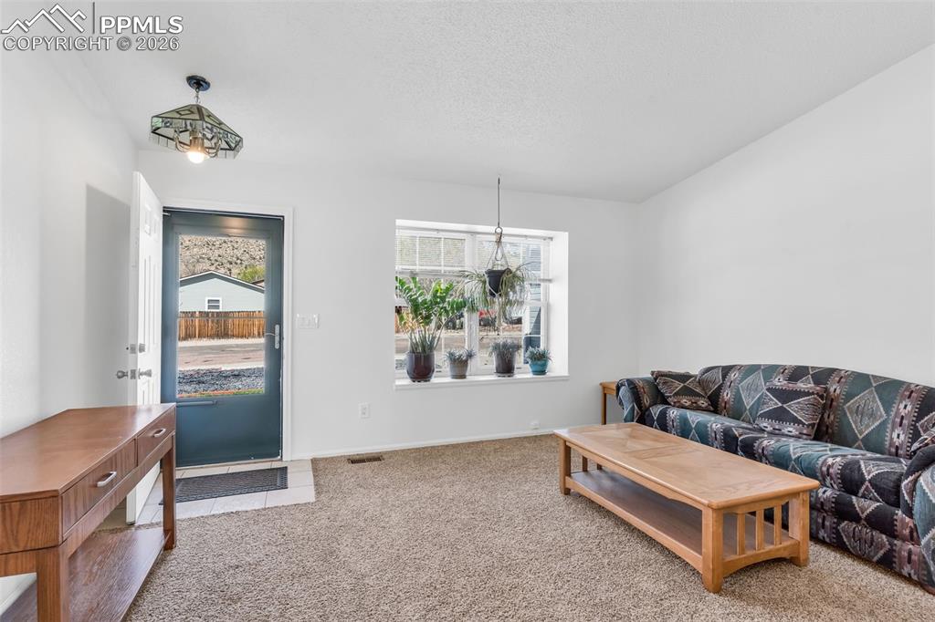 Image 5 of 27: Inviting front entry with tile landing and living area featuring a large pi