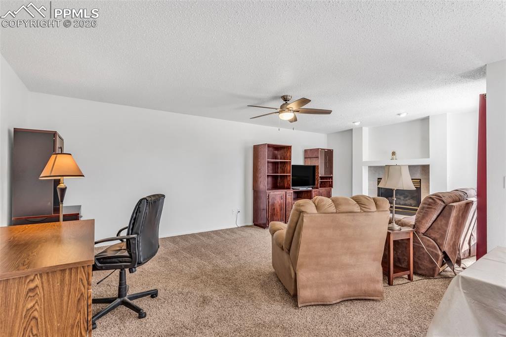 Image 9 of 27: Generous living area with ceiling fan, and plenty of space for a home offic