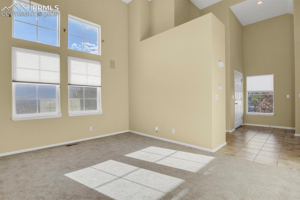 Image 14 of 45: Empty room featuring light colored carpet, a towering ceiling, and light ti