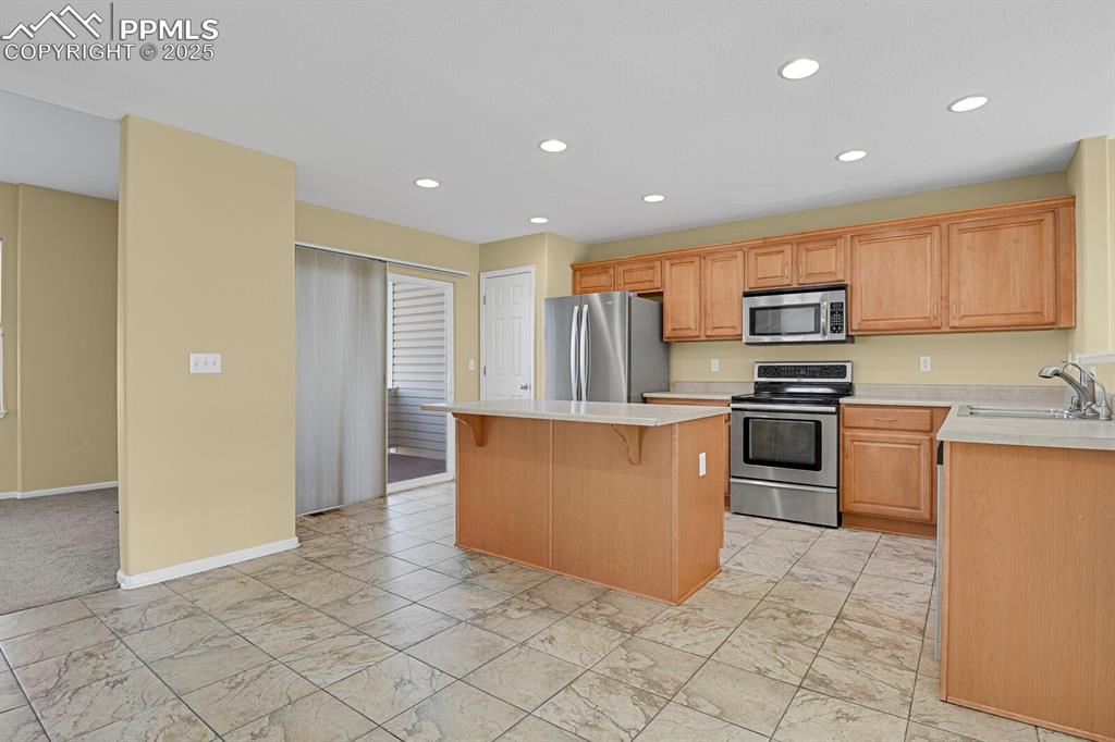 Image 19 of 45: Kitchen with stainless steel appliances, light countertops, recessed lighti