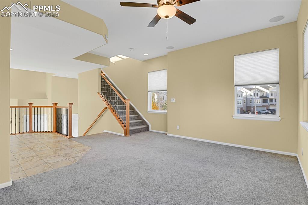 Image 25 of 45: Unfurnished room featuring light carpet, ceiling fan, stairs, and recessed
