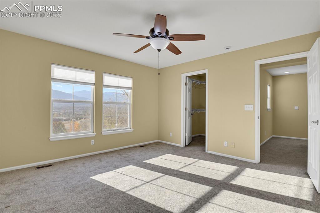 Image 32 of 45: Unfurnished bedroom with light carpet, a spacious closet, and a ceiling fan