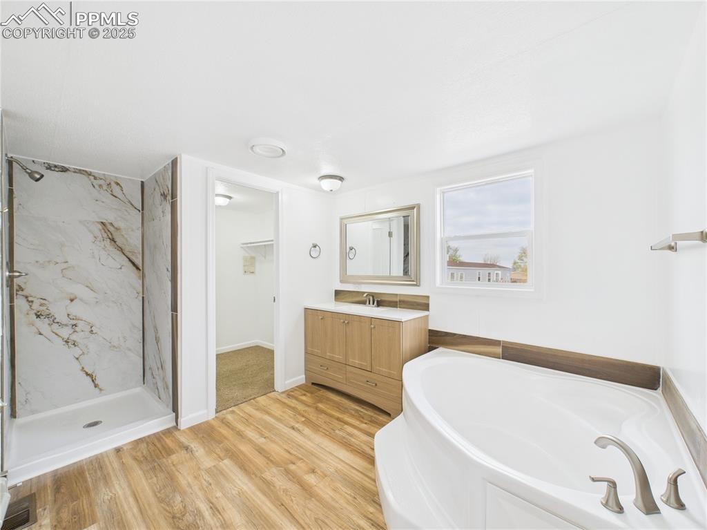 Image 16 of 34: Full bathroom with a garden tub, vanity, and a marble finish shower