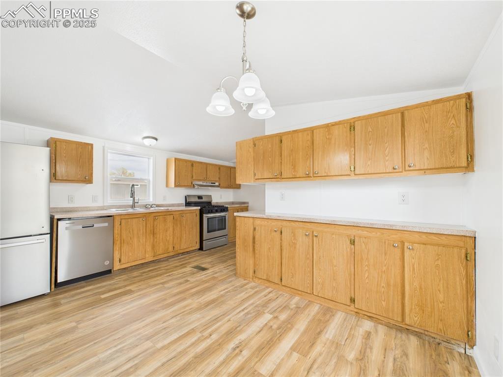 Image 8 of 34: Kitchen featuring an inviting chandelier, light countertops, light wood-typ