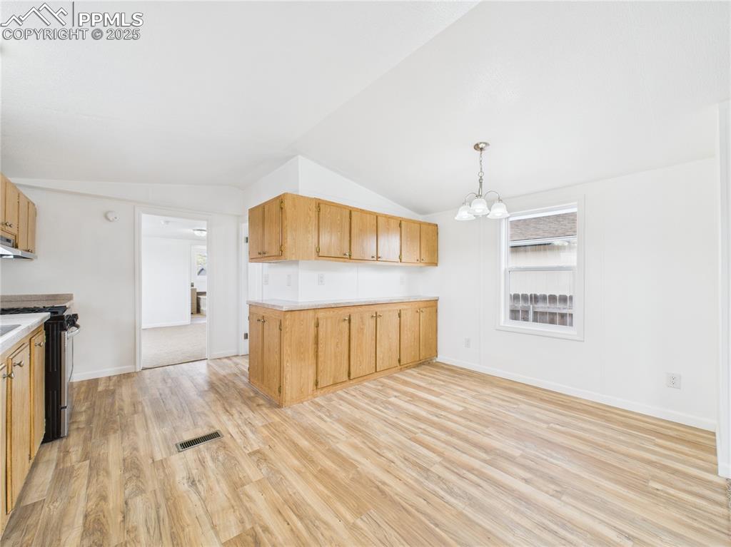 Image 9 of 34: Kitchen featuring light wood-type flooring, light countertops, lofted ceili