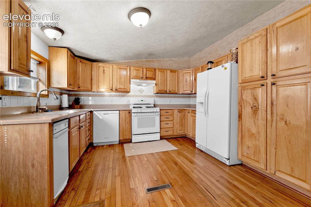 Image 11 of 48: Kitchen featuring a textured ceiling, sink, light wood-type flooring, and w