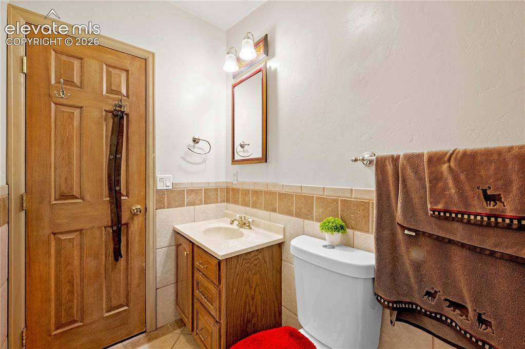 Image 18 of 48: Bathroom featuring vanity, toilet, tile patterned floors, and tile walls