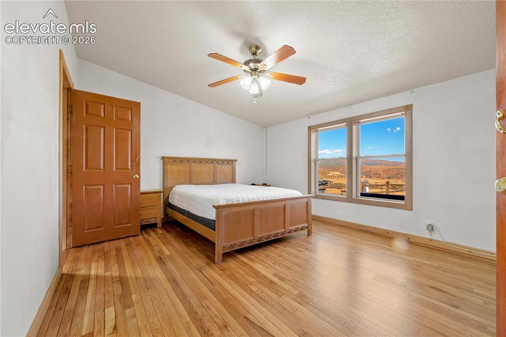Image 22 of 48: Bedroom with vaulted ceiling, a textured ceiling, light hardwood / wood-sty