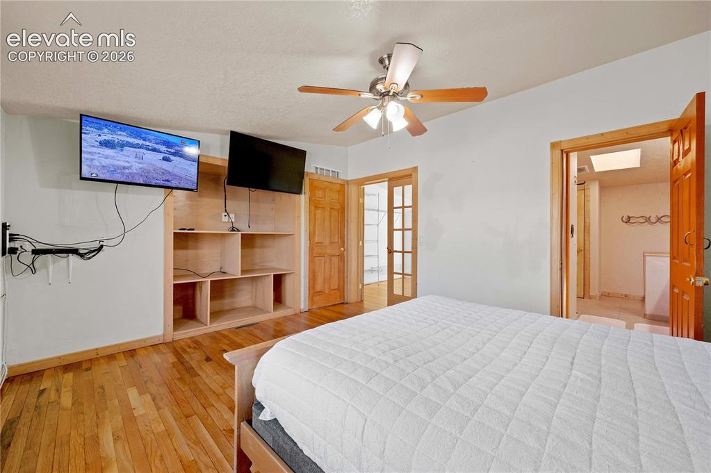 Image 24 of 48: Bedroom featuring a textured ceiling, hardwood / wood-style flooring, a sky