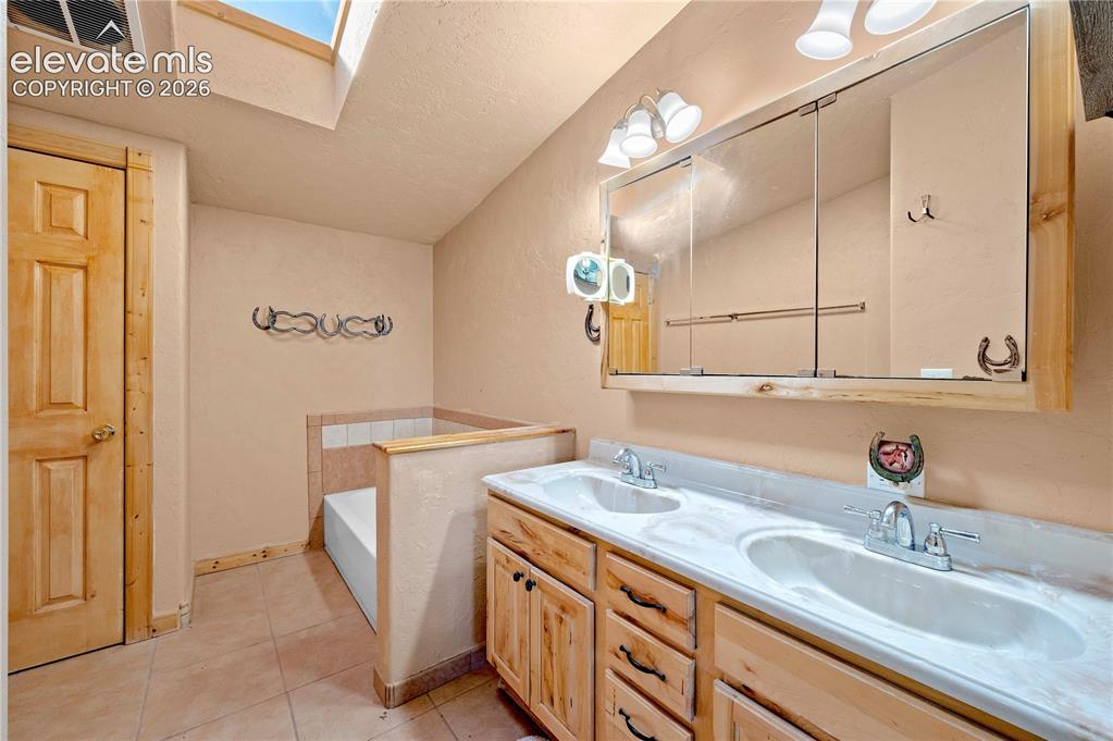 Image 26 of 48: Bathroom with tile patterned floors, a bathtub, vanity, a textured ceiling,