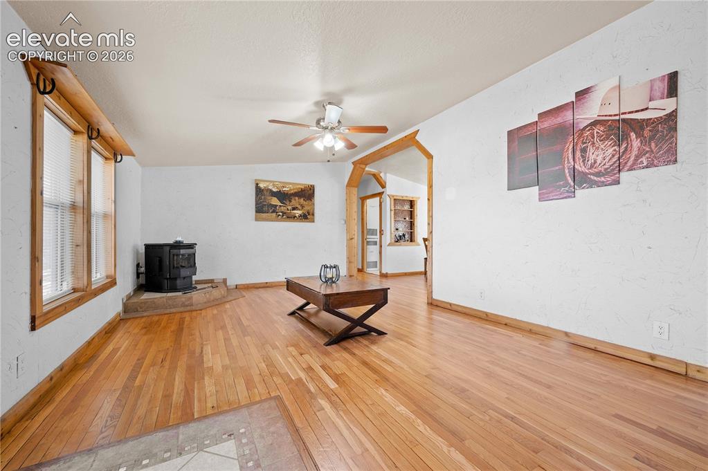 Image 6 of 48: Unfurnished living room with lofted ceiling, wood-type flooring, a wood sto