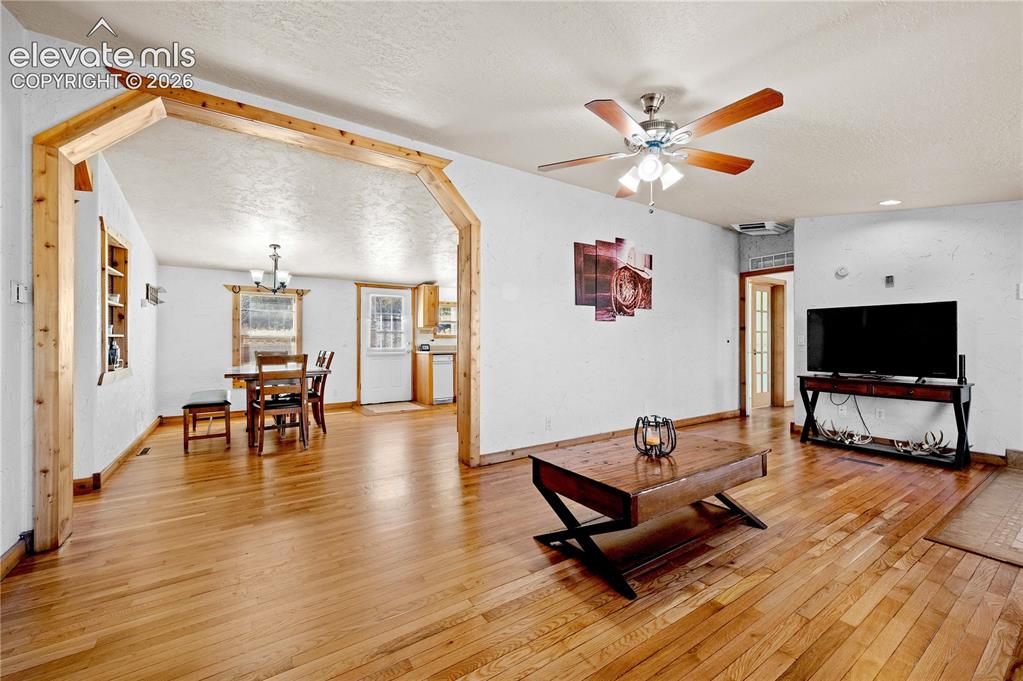 Image 8 of 48: Living room featuring a textured ceiling, ceiling fan with notable chandeli