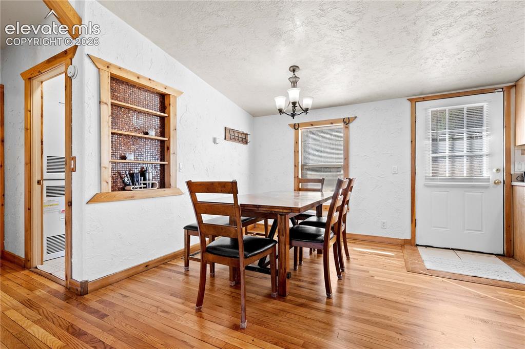 Image 9 of 48: Dining room with hardwood / wood-style floors, a chandelier, a textured cei