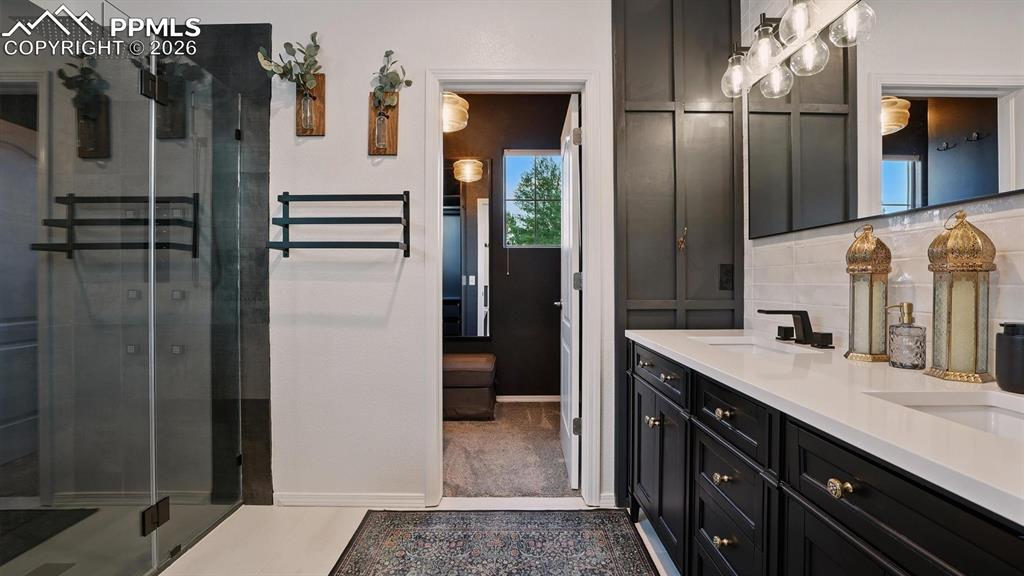 Image 22 of 50: The Primary Bathroom has a tile floor, dual sink vanity, and walk in shower