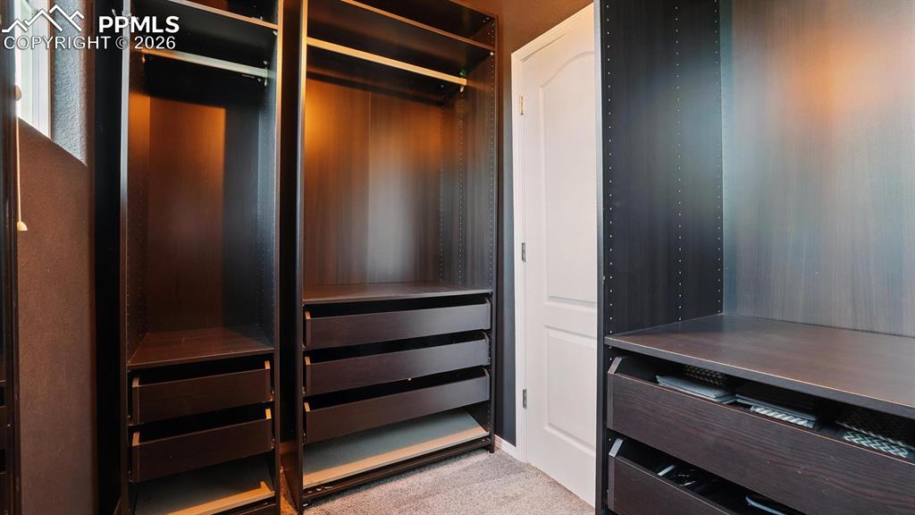 Image 25 of 50: Walk in closet with custom organizers in the Primary Suite.