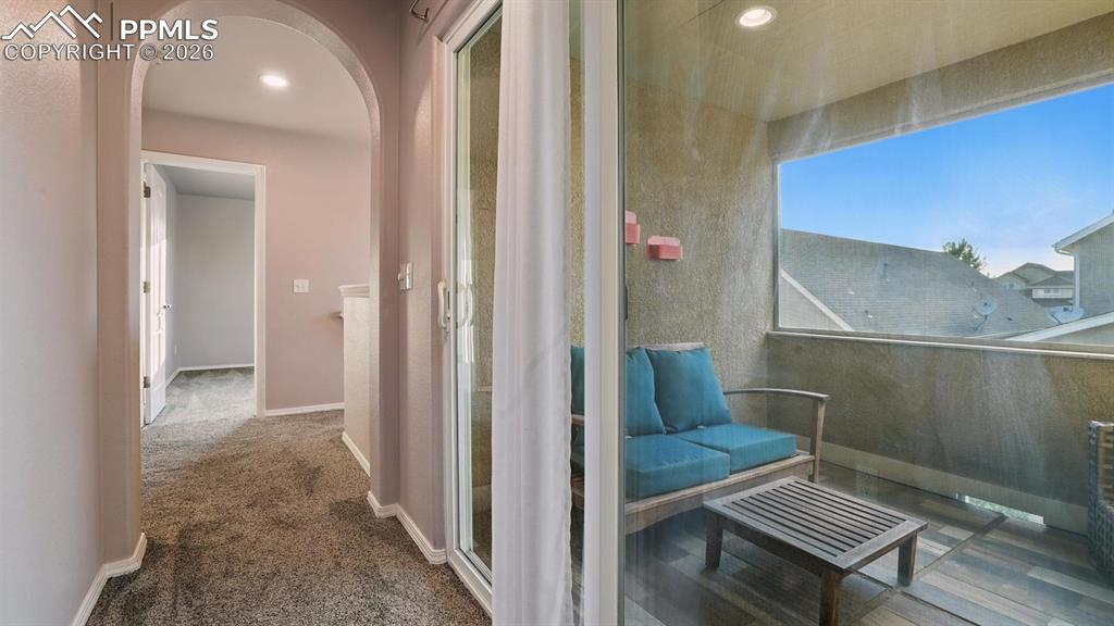 Image 27 of 50: Walk out to a covered balcony located off the hallway of the upper level.