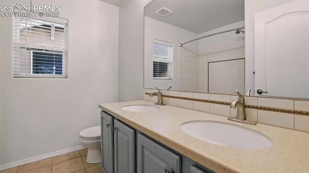 Image 30 of 50: Upper Level Full Hall Bathroom with dual sink vanity, mirror, and tiled tub