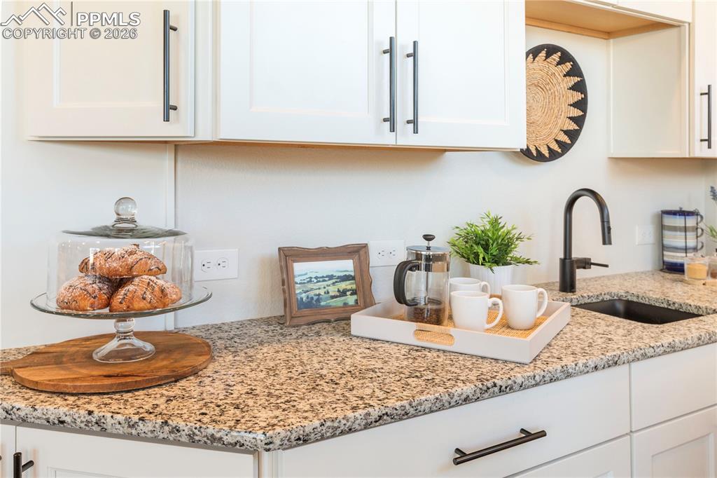 Image 20 of 50: Kitchen view of light stone counters and white cabinets