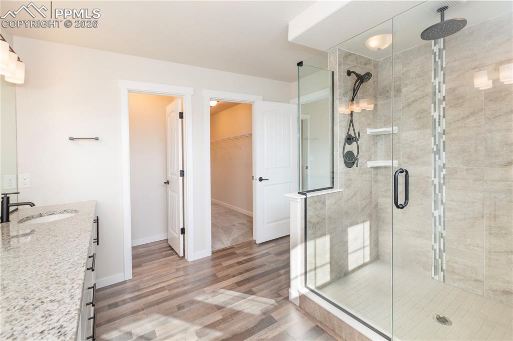 Image 31 of 50: Two shower heads including an overhead Rain shower and a bench.