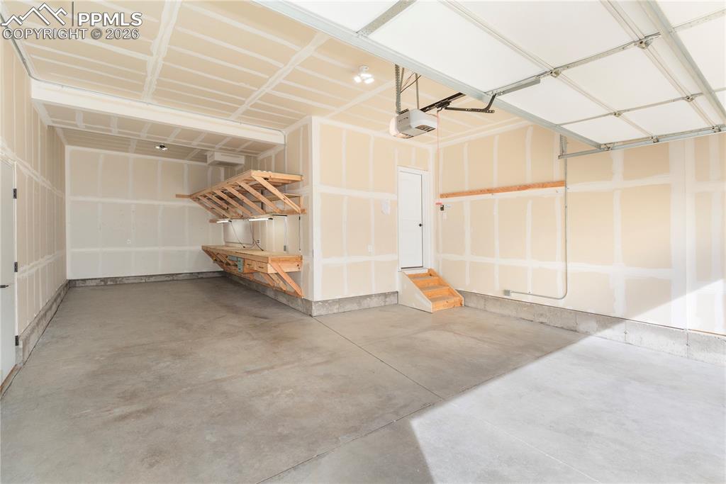 Image 47 of 50: 3-car garage features a custom workshop with built-in storage and lighting.