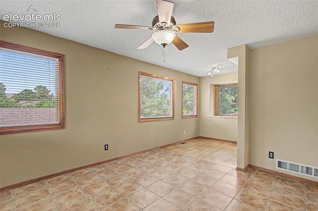 Image 12 of 44: Room featuring light beige walls, wood-trimmed windows, a ceiling fan with