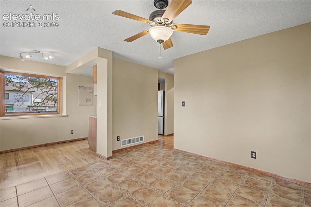 Image 13 of 44: Open living space with ceiling fan and mixed flooring
