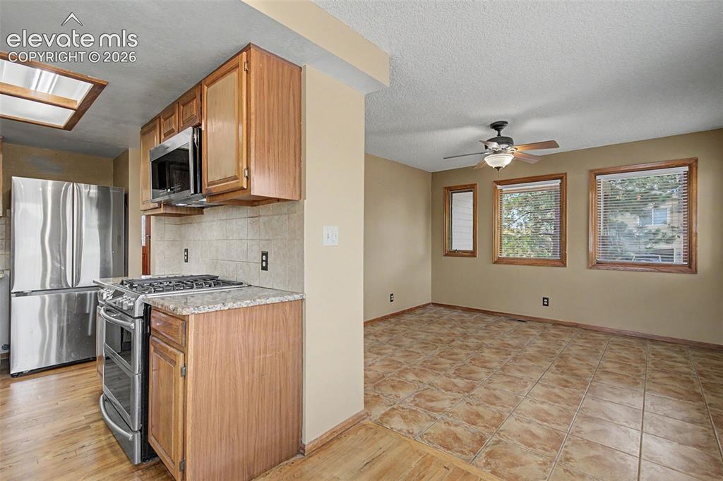Image 15 of 44: Kitchen and living area featuring a stainless steel gas range, microwave, a