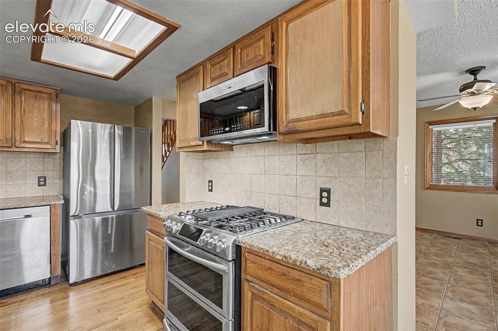 Image 16 of 44: Kitchen featuring wood cabinetry, stainless steel appliances, granite count