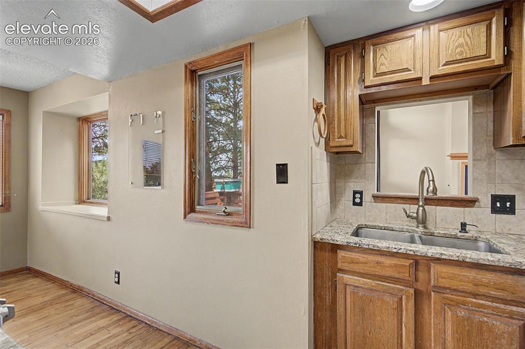 Image 20 of 44: Kitchen area with wood-finish flooring, oak cabinetry, and granite countert