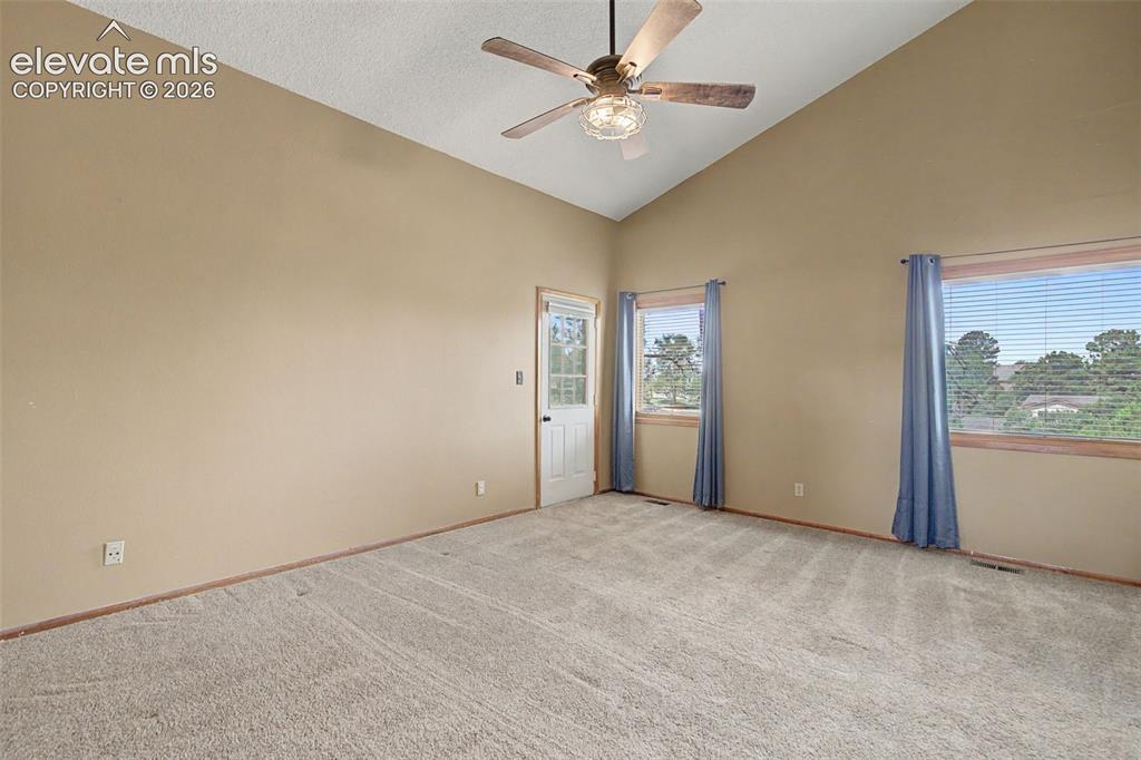 Image 25 of 44: Carpeted room featuring a vaulted ceiling with a ceiling fan, a white panel