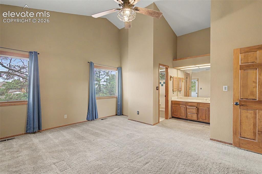 Image 26 of 44: Vaulted ceiling room featuring light-toned carpeting, two windows with wood