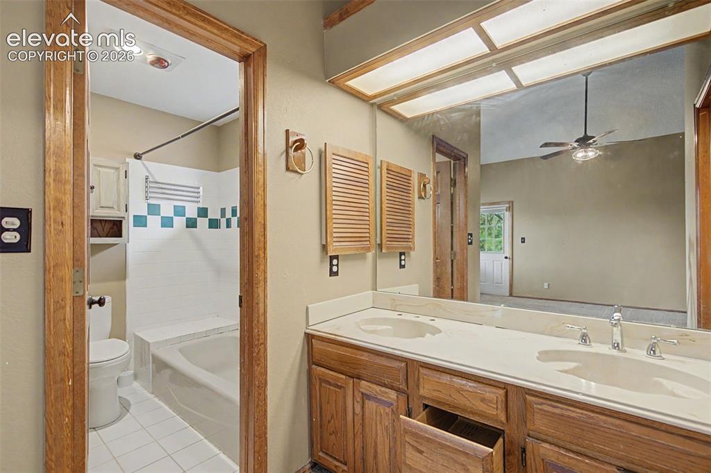 Image 29 of 44: Bathroom featuring a dual vanity with wood-finish cabinetry, a white counte