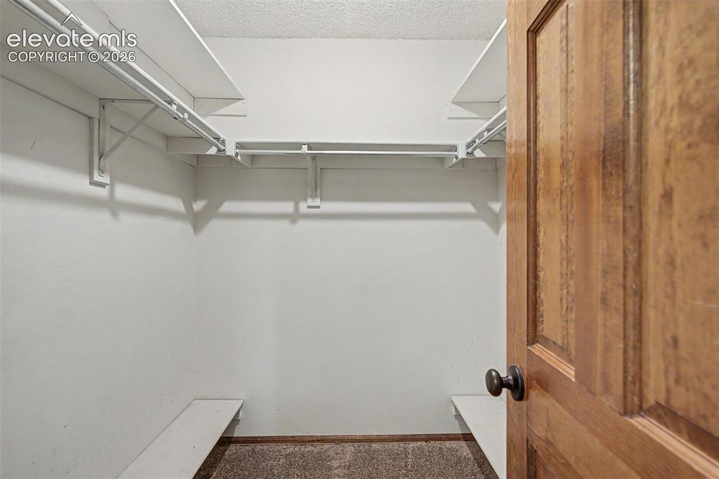Image 31 of 44: Walk-in closet featuring white wire shelving, hanging rods, and an overhead