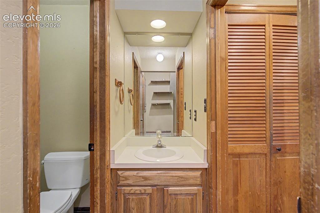 Image 38 of 44: Bathroom vanity featuring an integrated sink, white countertop, and wood-fi