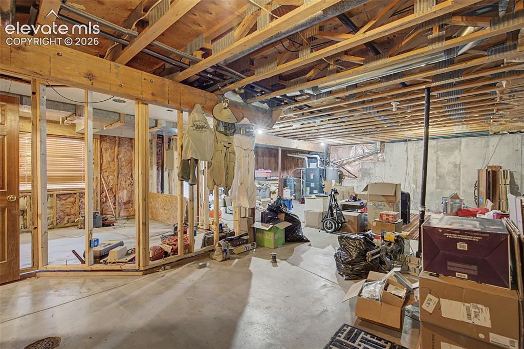 Image 39 of 44: Unfinished basement featuring exposed wood joists and concrete walls, with