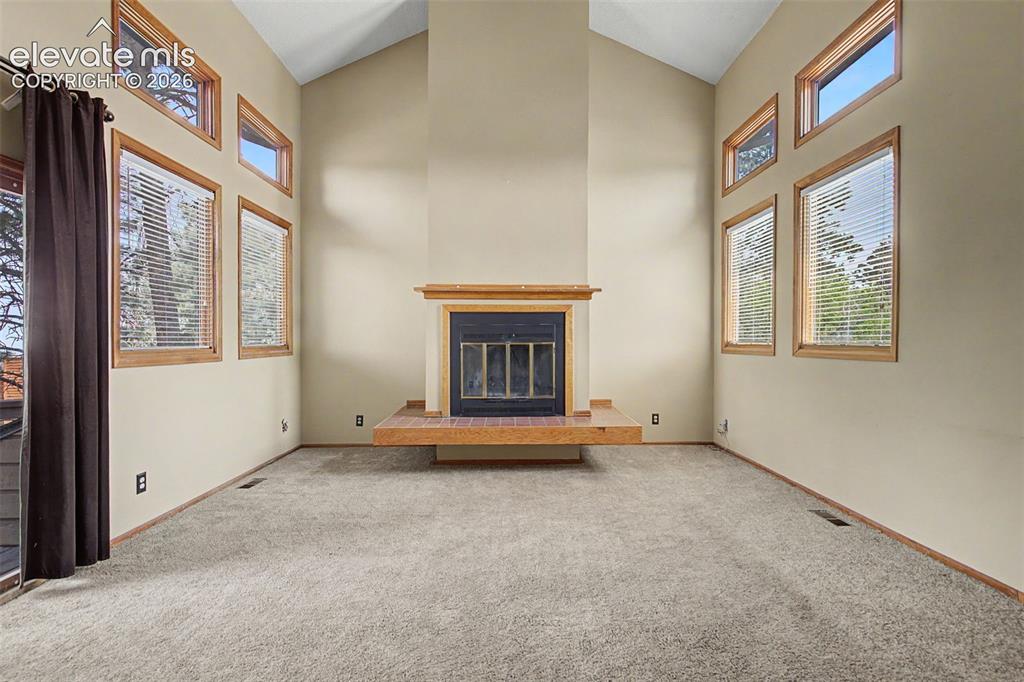 Image 7 of 44: Vaulted ceiling room featuring a central fireplace with a floating wood hea