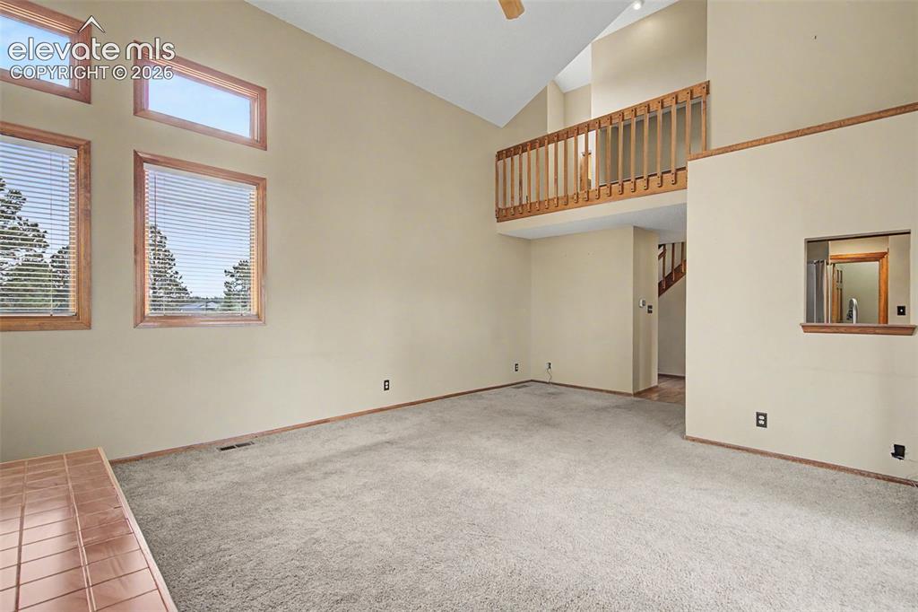 Image 8 of 44: Living area with vaulted ceilings, a balcony overlooking the space, and mul